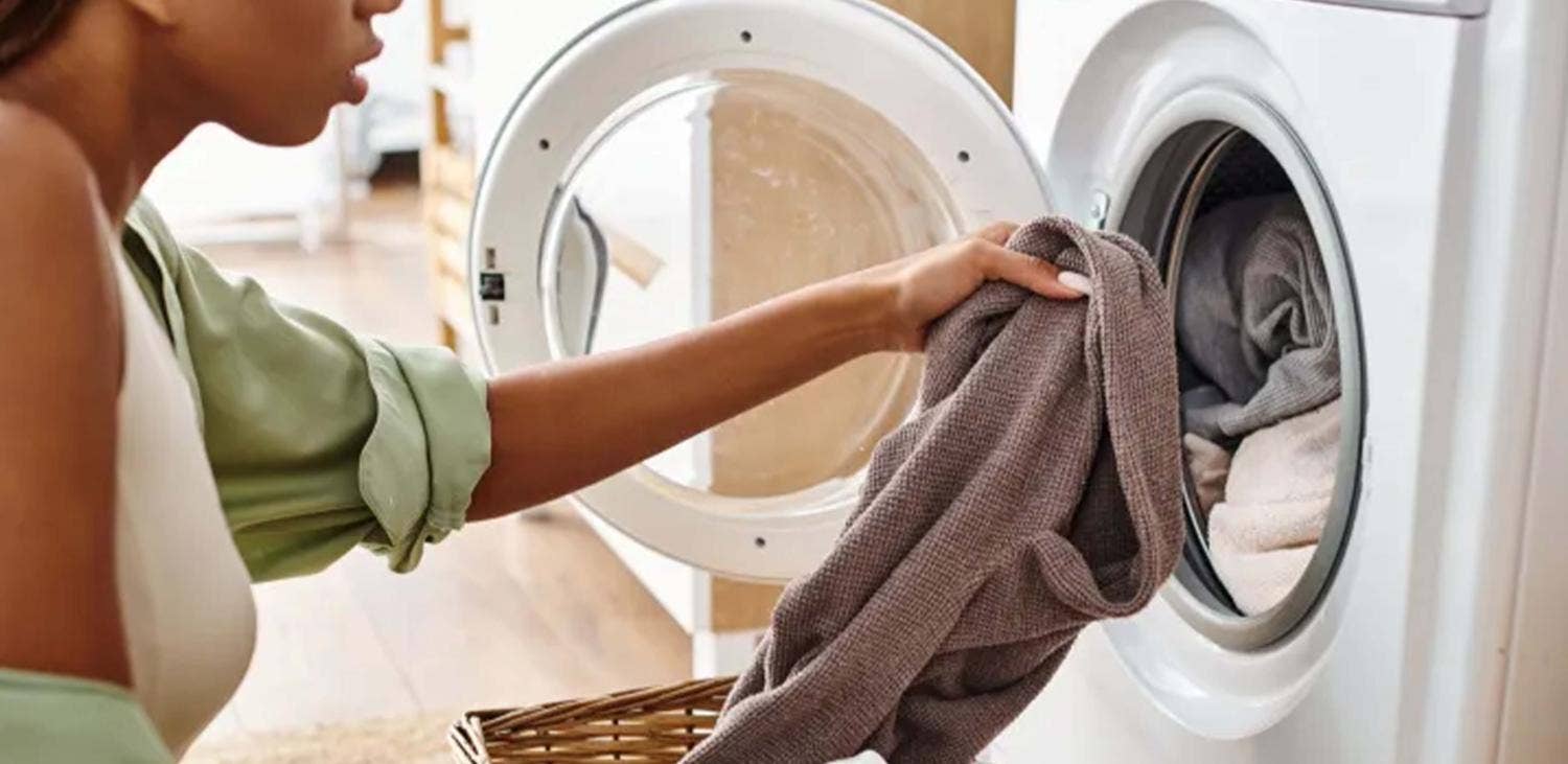Vrouw stopt wasgoed in warmtepompdroger. Vrouw stopt wasgoed in warmtepompdroger.